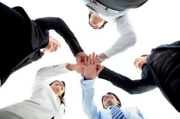 Business team with their hands together in the middle isolated over white